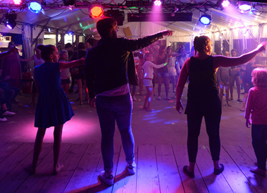Artiesten leiden een dorpsdans op het podium tijdens een levendige avond op Camping Les Pins d'Oléron.